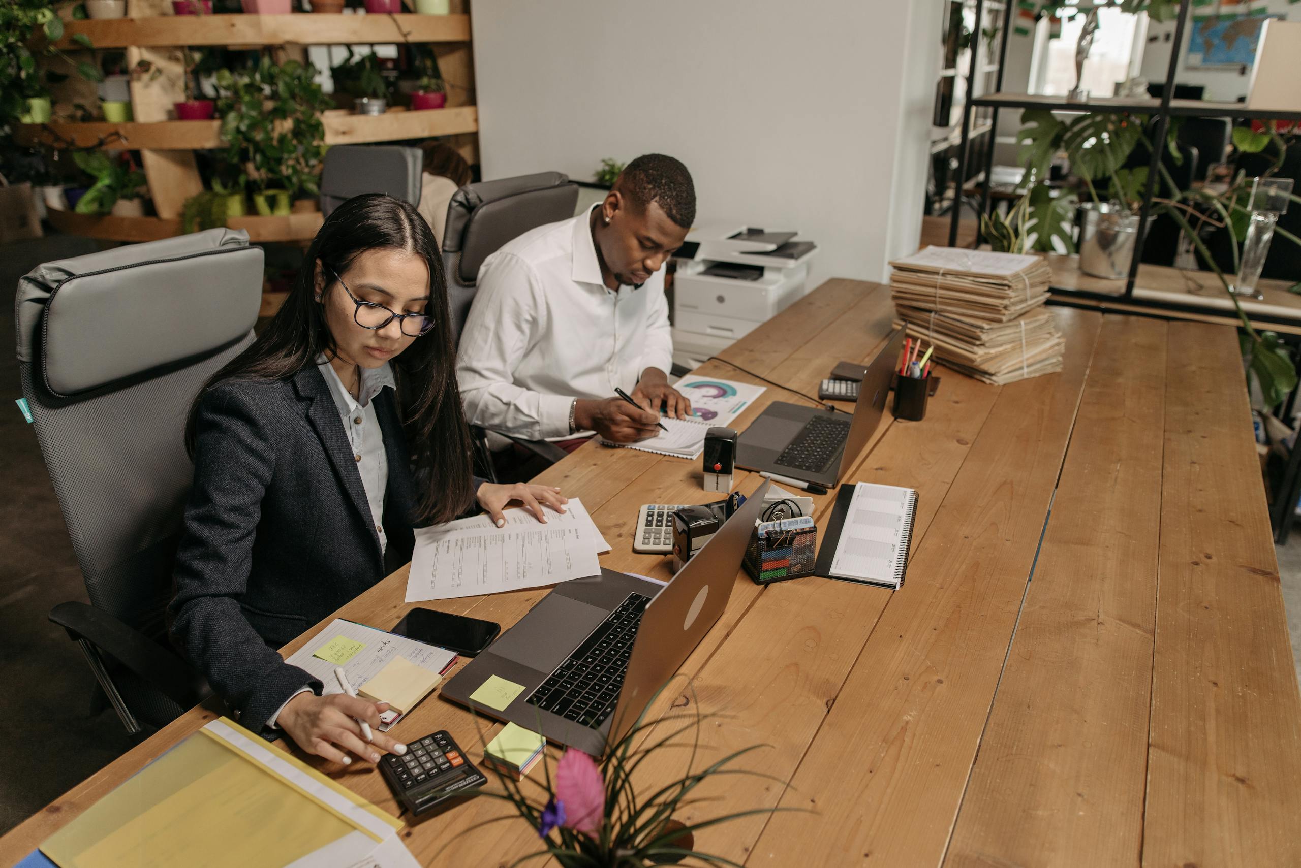 Asian woman and African American man working with laptops in a modern office setting. Collaboration and teamwork.